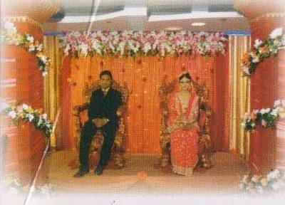 A bride and groom seated on a decorated wedding stage with flowers