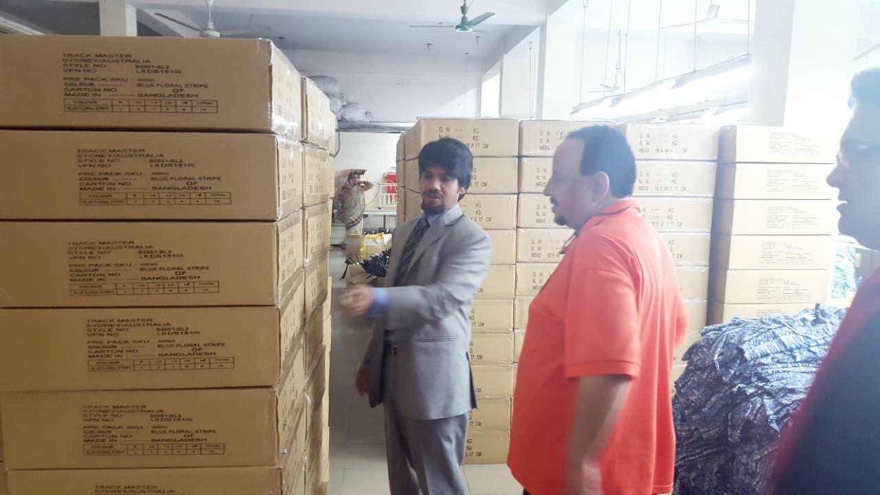 Management and a buyer beside stacked export cartons