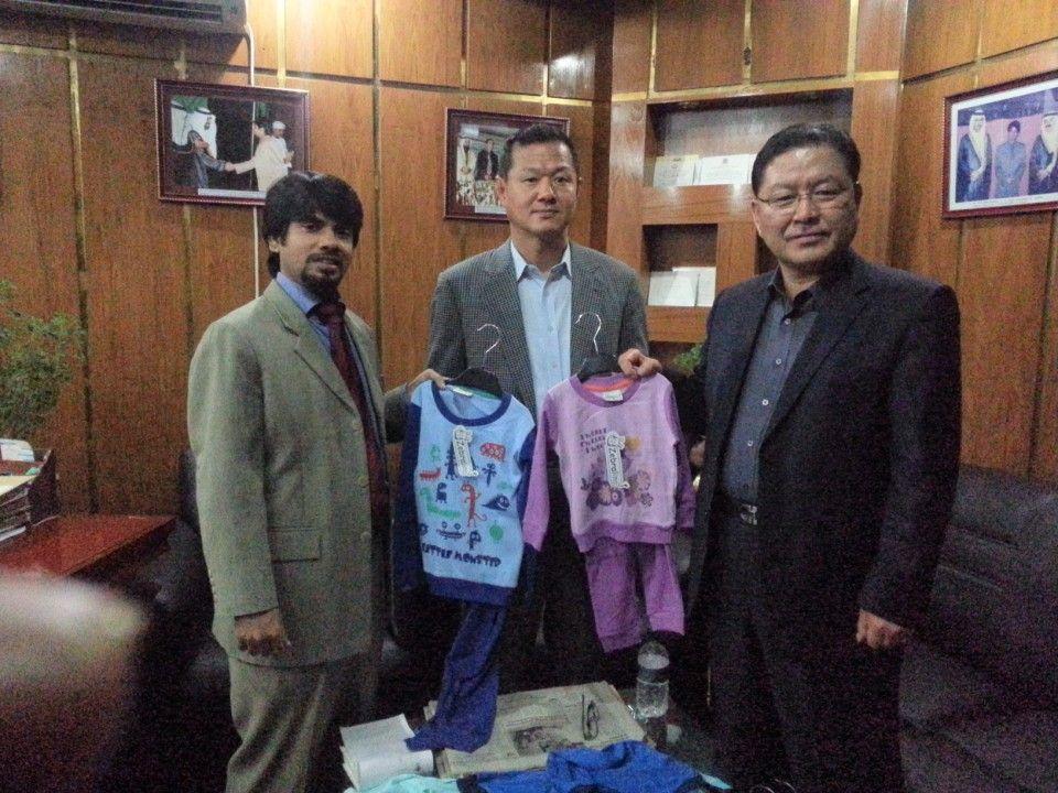 Visiting buyers holding children's pyjama sets in the Chairman's office